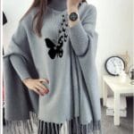 Lifestyle image of model wearing grey butterfly poncho outdoors