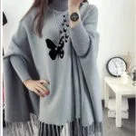Lifestyle image of model wearing grey butterfly poncho outdoors