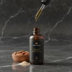 Almond oil in glass bottle with nuts – natural beauty oil